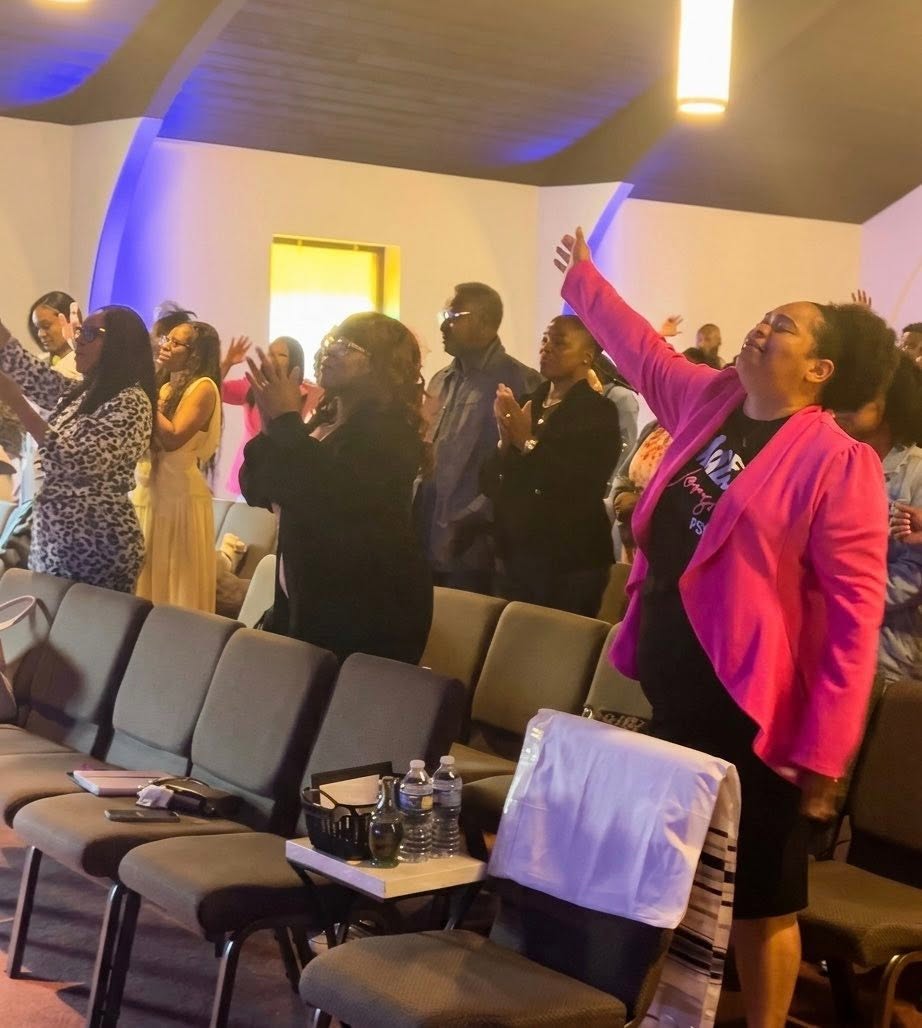 Members of the congregation with hands raised during a Sunday service